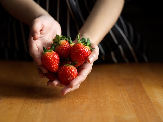 vrouwelijke hand met aardbeien op houten keukentafel