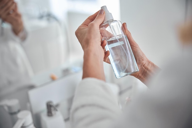 Vrouwelijke hand met crème fles lotion in de badkamer