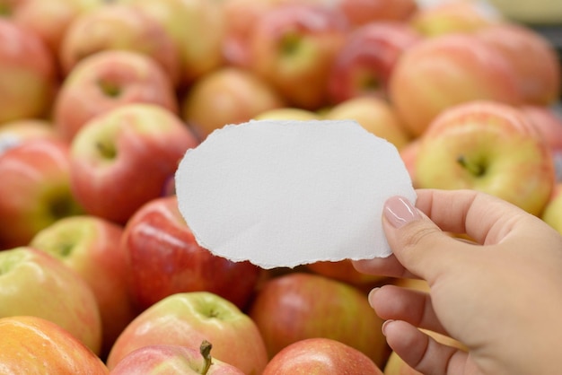 Vrouwelijke hand met een gescheurd stuk papier voor een plank met bananen Inkooplijstconcept