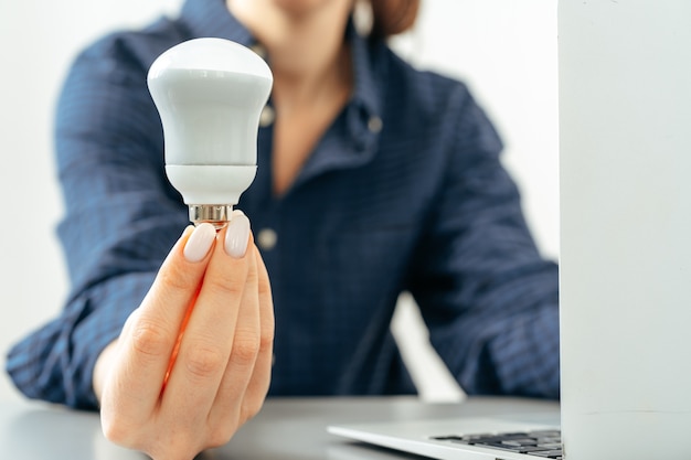 Vrouwelijke hand met een gloeilamp boven de tafel