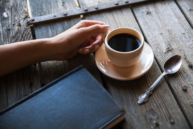 Vrouwelijke hand met een kopje koffie, notities maken. Het werkt records. Bedrijf