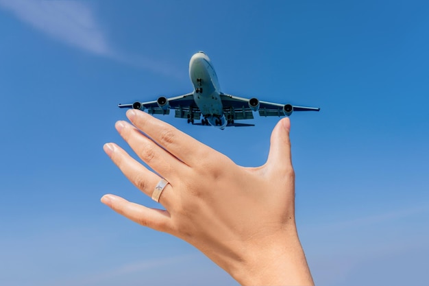 Vrouwelijke hand met een ring met een getekend vliegtuig dat een vliegtuig vasthoudt dat in de lucht vliegt op een reis