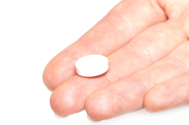 Vrouwelijke hand met een witte medicinale tablet in de palm van de hand.white background