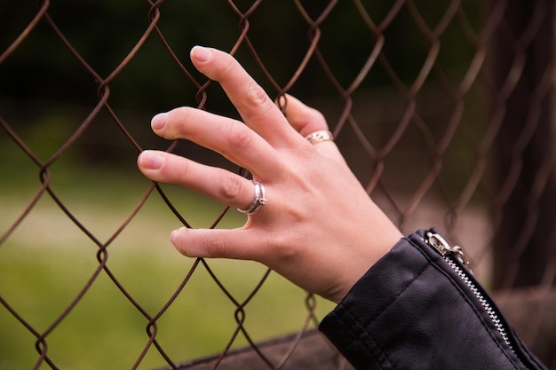 Foto vrouwelijke hand met gaasomheining, geen vrijheid voelen