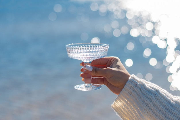 Vrouwelijke hand met glas water met zee achtergrond