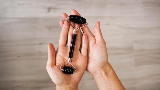 Vrouwelijke hand met jade steen gezichtsroller massage tool voor de huid;