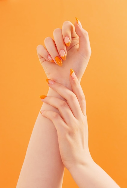 Vrouwelijke hand met manicure op oranje achtergrond