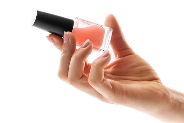 Vrouwelijke hand met mooie french manicure met fles roze nagellak tegen witte achtergrond