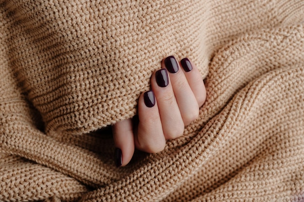 Vrouwelijke hand met mooie nagels Gezonde nagels Gemanicuurde handen met gebreide wollen stof