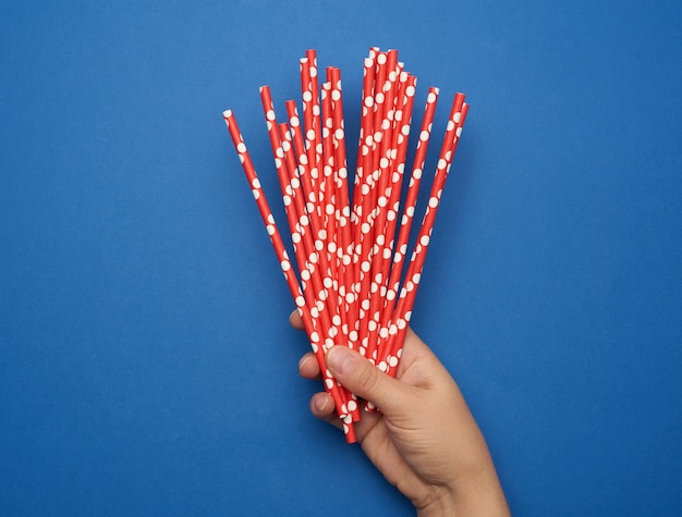 Foto vrouwelijke hand met papieren rode cocktailbuizen, afwijzing van plastic, nul afval