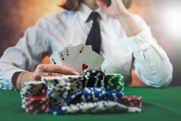 Vrouwelijke hand met speelkaarten en chips aan een ronde pokertafel riskante weddenschappen in poker geïsoleerd