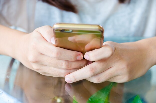 vrouwelijke hand met telefoon op glazen tafel