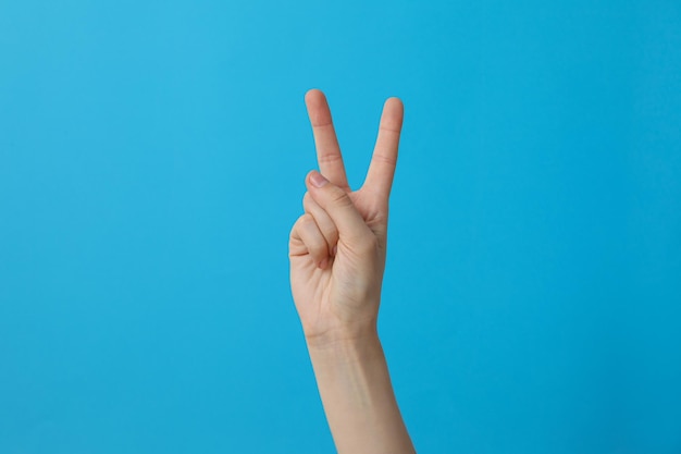 Foto vrouwelijke hand met twee vingers op een blauwe achtergrond