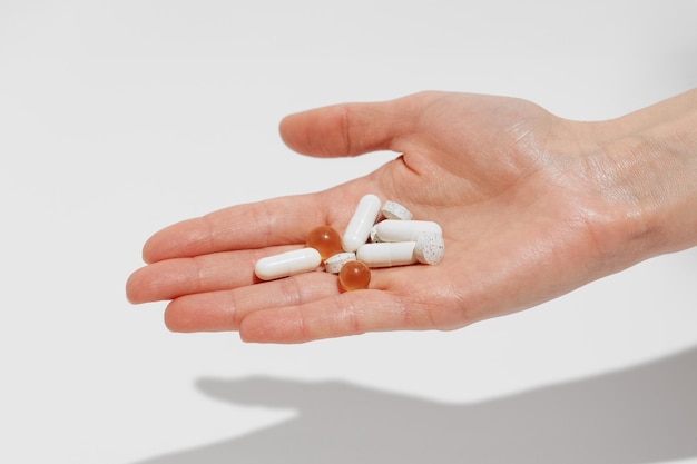 Vrouwelijke hand met witte pillen en capsules op een witte geïsoleerde achtergrond Concept van apotheek gezondheidsmedicine en voedingssupplementen Afbeelding voor uw ontwerp