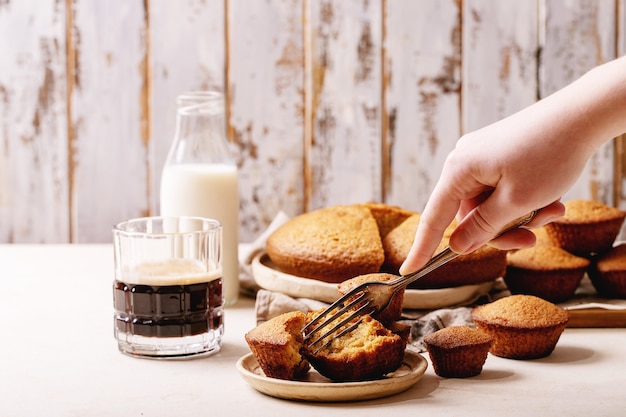 Vrouwelijke hand met zelfgemaakte muffins geserveerd met koffie op witte textuur achtergrond