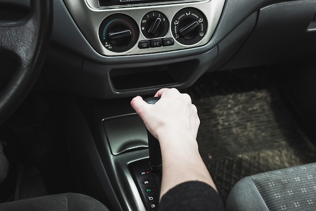 Vrouwelijke hand op de automatische transmissie van de schakelhendel.