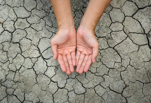 Vrouwelijke hand op droge, gebarsten grond