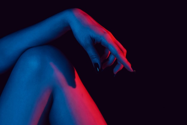 Vrouwelijke hand op knie dichte omhooggaand met neonlicht