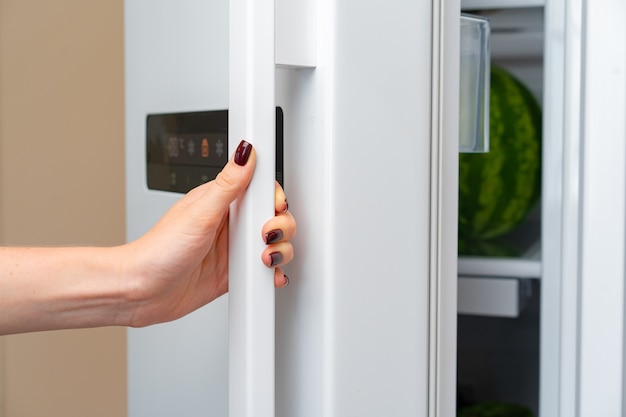 Vrouwelijke hand opent deur van een koelkast