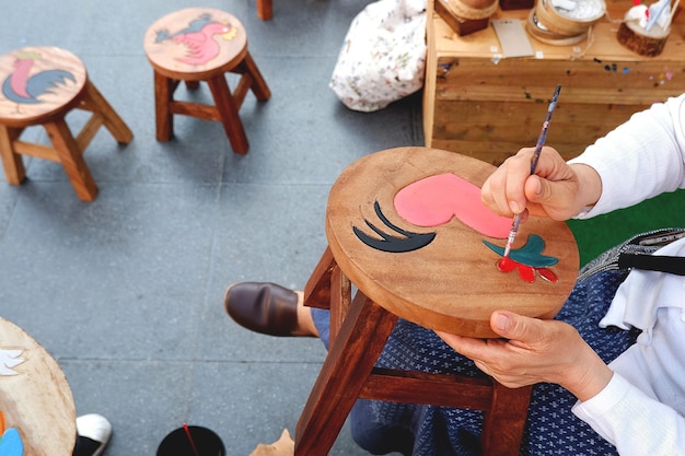 vrouwelijke hand schilderij foto op tamarinde houten stoel op workshop