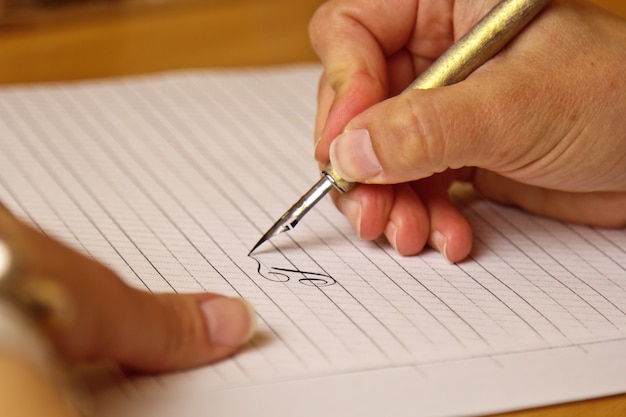 Vrouwelijke hand schrijft met een inkt pen op een vel wit papier met strepen.