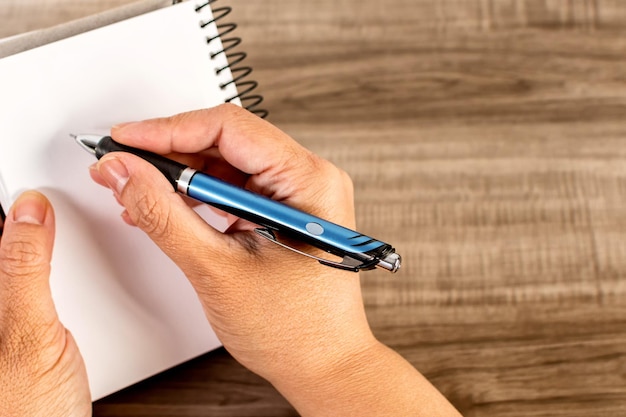 Vrouwelijke hand schrijven in een notitieblok op houten tafel