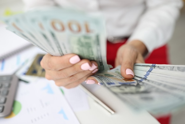 Vrouwelijke hand tellen contant geld in kantoor. Veel honderd dollar
