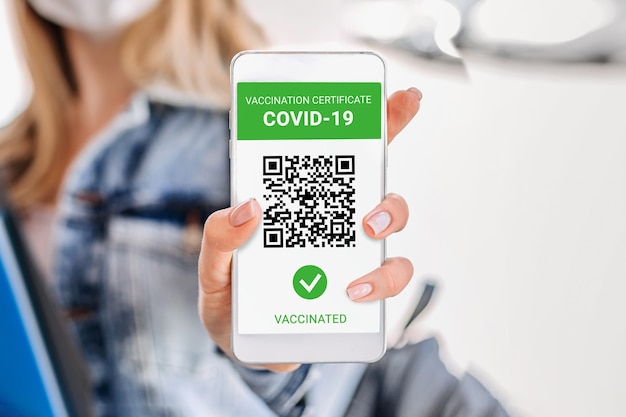 Vrouwelijke hand toont smartphone-display met mobiele app gevaccineerde covid-19. internationaal coronavirus certificaat