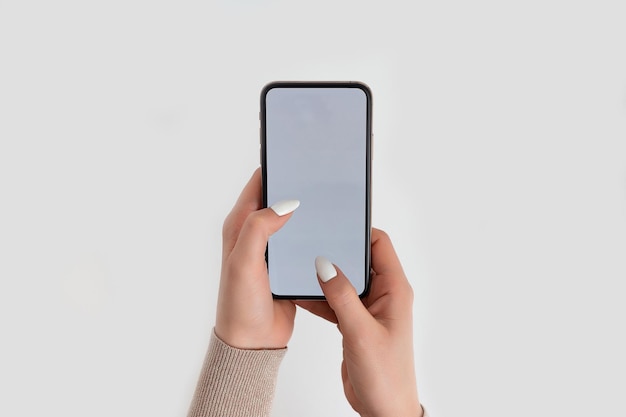 Vrouwelijke hand vasthouden en aanraken op mobiele smartphone met wit scherm Geïsoleerd op wit Fotosjabloon voor afbeeldingen op het display van de mobiele telefoon Lay-out met gemakkelijk verwijderbare telefoonmonitorachtergrond