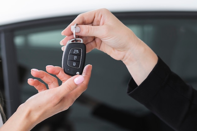 Foto vrouwelijke handelaar die sleutels aanbiedt aan een auto