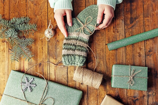 Vrouwelijke handen bereiden cadeaus voor kerstmis op houten tafel