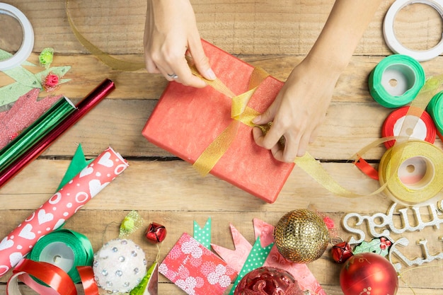 Vrouwelijke handen binden een kerstdoos met lint