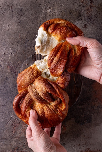 Vrouwelijke handen breken een rieten broodje op een donkere achtergrond