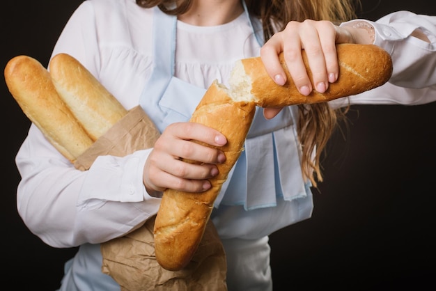 Vrouwelijke handen breken vers stokbrood brood close-up