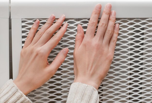 vrouwelijke handen controleren de verwarmingsradiator op warmte en zetten de verwarming aan of uit