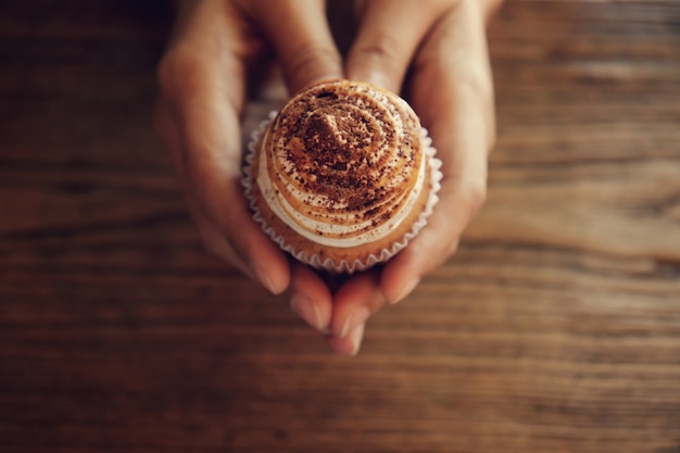 Foto vrouwelijke handen die cupcake houden