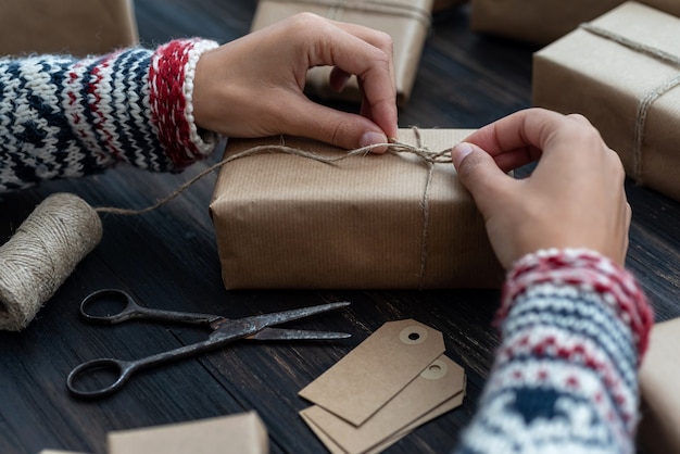 Vrouwelijke handen die de doos van de kerstmisgift omhullen