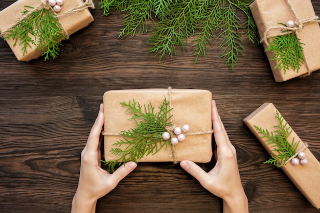 Vrouwelijke handen die de doos van de Kerstmisgift op donker hout houden