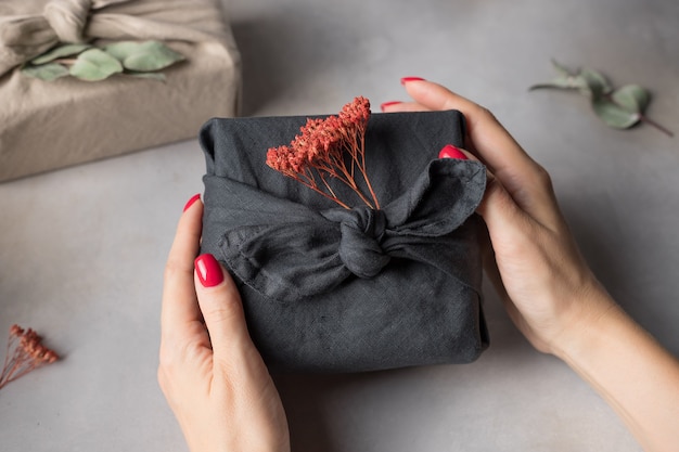 Vrouwelijke handen die een Furoshiki-cadeau vasthouden Geen afval cadeaupapier