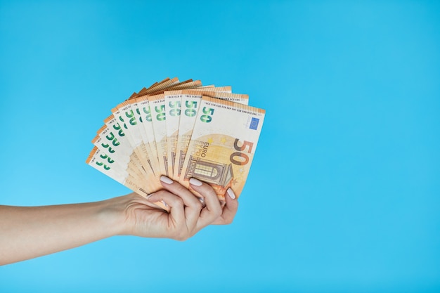 Vrouwelijke handen die euro bankbiljetten op blauw houden.