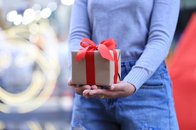 Vrouwelijke handen die giftdoos met rood lint houden voor Kerstmis en Nieuwjaarsdag of Groetseizoen, Valentijnskaartendag