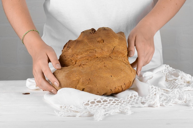 Vrouwelijke handen die het brood van Matera Pane di Matera op een witte achtergrond zetten, typisch zuidelijk Italiaans zuurdesembrood