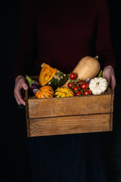 Vrouwelijke handen die houten doos met groentenassortiment houden