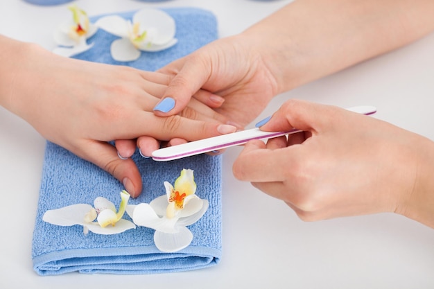 Vrouwelijke handen doen manicure Potten crème een nagelvijl gerbera met waterdruppels op een lichtroze pluche achtergrond