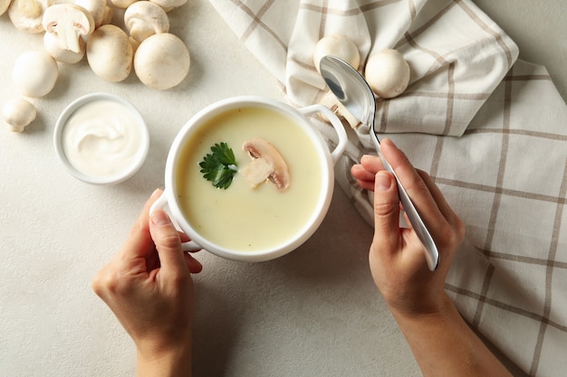 Vrouwelijke handen en kom smakelijke champignonsoep