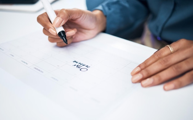 Foto vrouwelijke handen en marker op de kalender voor belasting deadline of herinnering in planning of strategie op het bureau op kantoor closeup van vrouwelijke persoon schrijven op papier voor agenda geheugen of plan op de werkplek