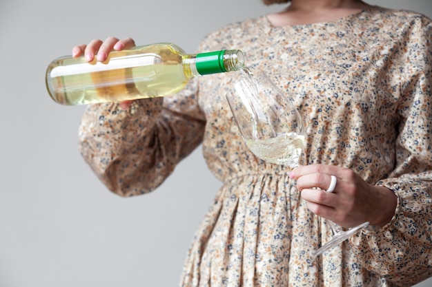 Vrouwelijke handen gieten witte wijn van fles tot glas