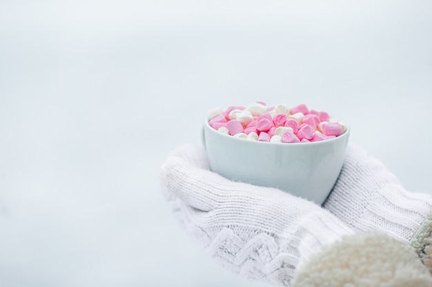 Vrouwelijke handen holdink witte kop koffie met witte en roze marshmallows