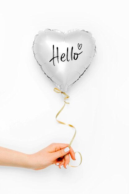 Vrouwelijke handen houden ballon van hartvormige folie op witte achtergrond. Liefdesconcept. Vakantie vieren. Valentijnsdag of bruiloft/vrijgezellenfeest decoratie. Metalen ballon