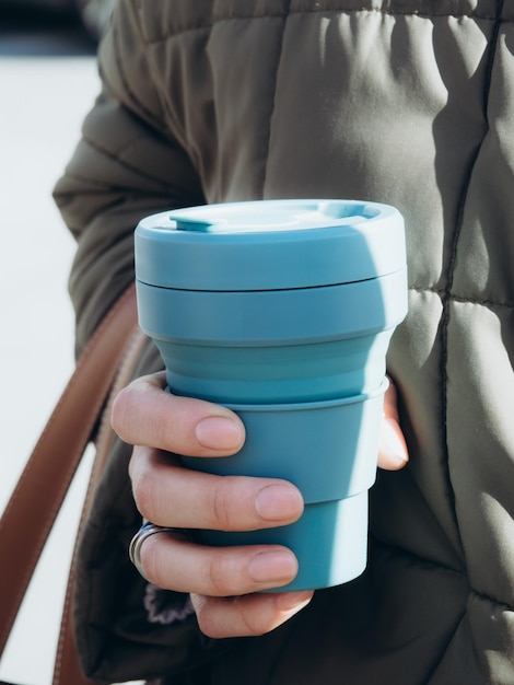 Foto vrouwelijke handen houden blauwe herbruikbare koffiemokken duurzame levensstijl milieuvriendelijk concept